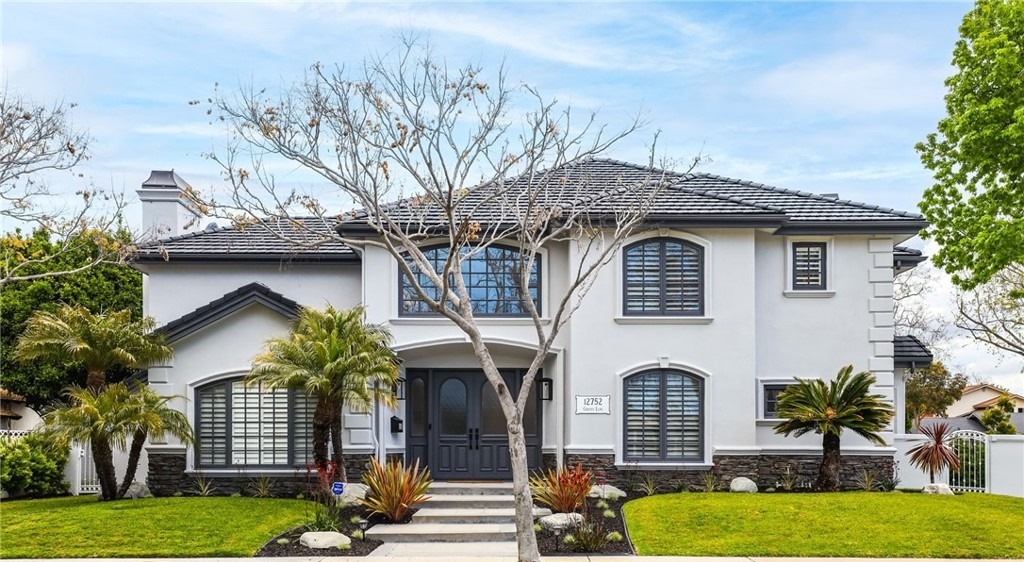 Front exterior of a two-story white residence with stone foundation and palm landscaping on Christy Ln, Rossmoor.