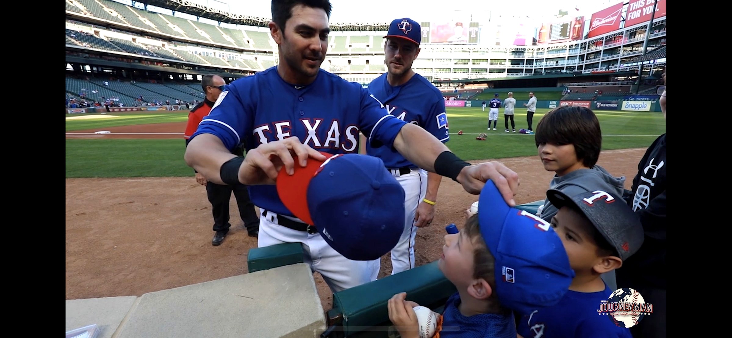 Chase d'Arnaud places a Texas Rangers cap on a young fan at the ballpark.