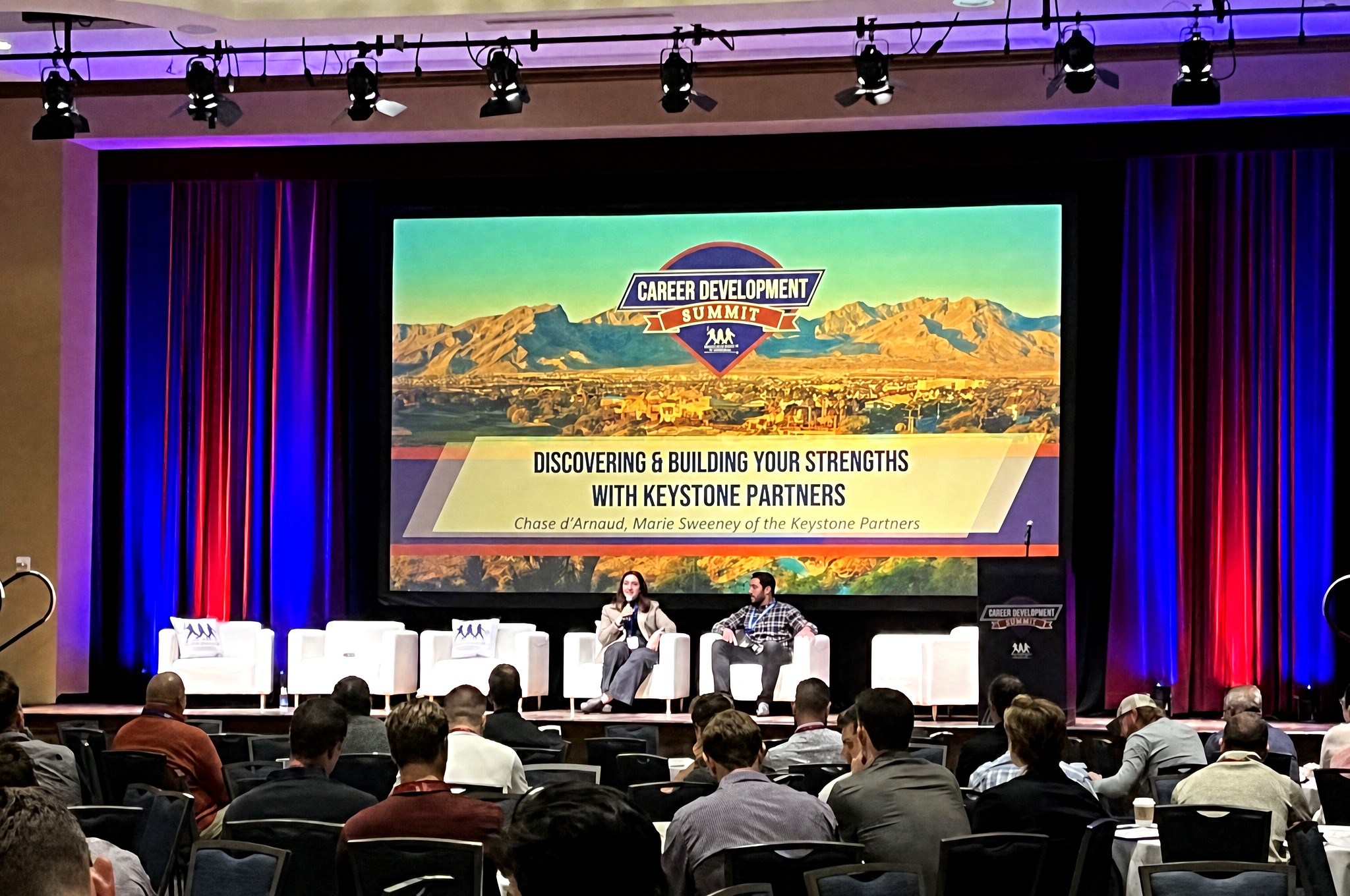 Chase d'Arnaud on a Career Development Summit panel before a seated audience, with Keystone Partners on screen.