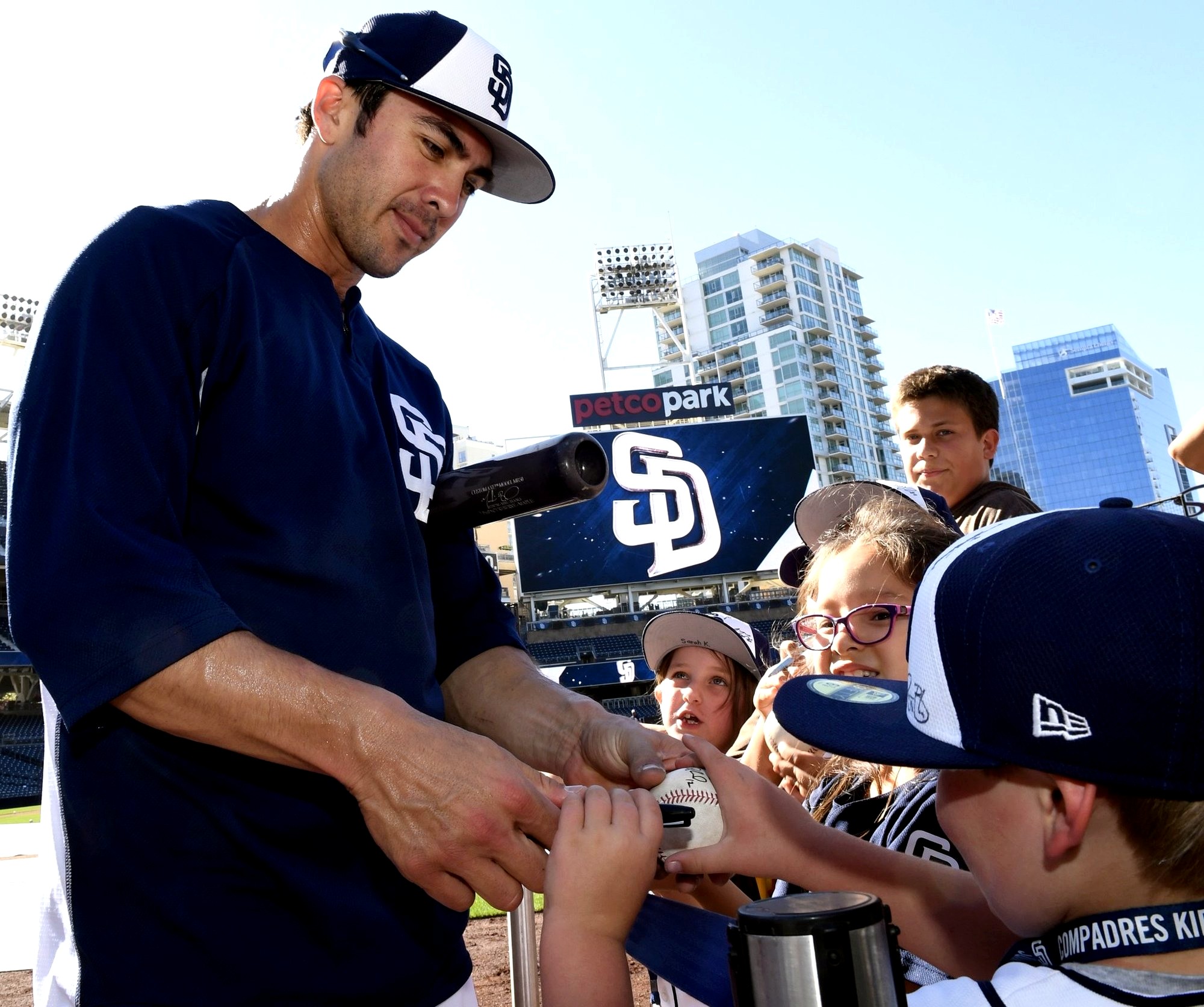 Chase d'Arnaud signs a baseball for young fans at a San Diego Padres game.